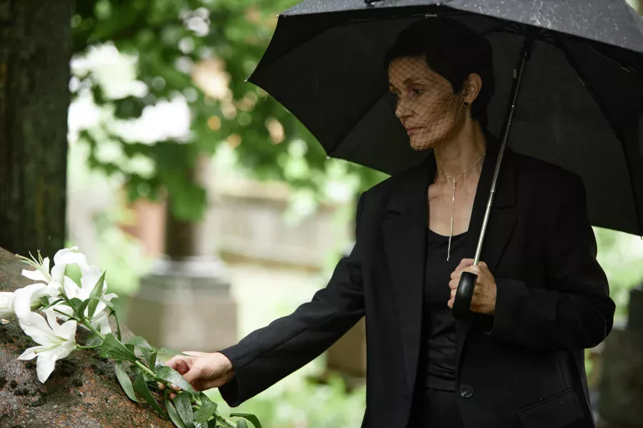 Short dark haired lady in appropriate funeral attire for women with mourning veil.