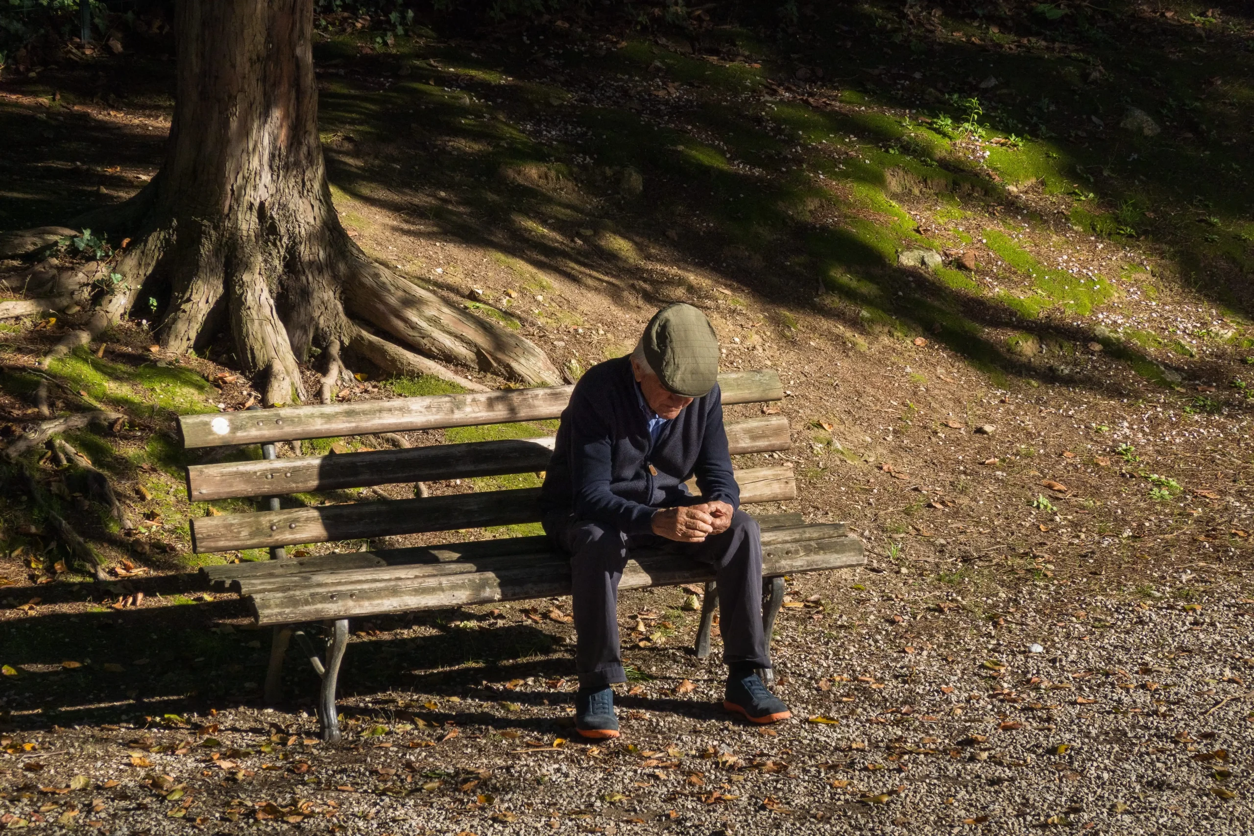 Elderly man sat on bench remembering someone on the anniversary of their death.